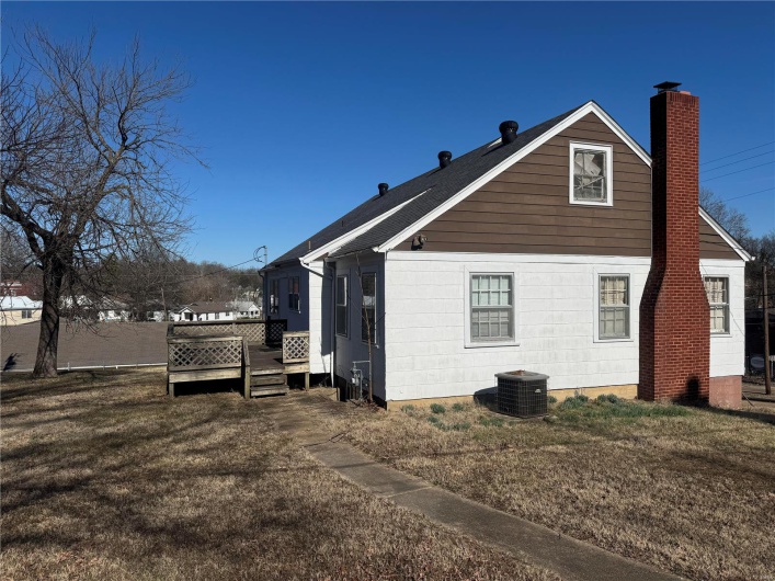 Rear view of house with a deck, a yard, central AC unit, and a chimney
