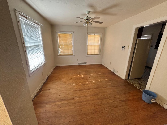 Unfurnished room with a ceiling fan, visible vents, and wood finished floors
