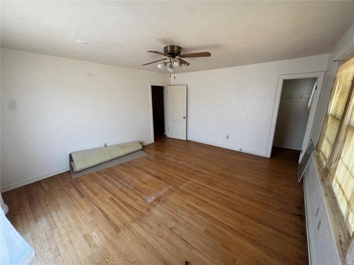 Spare room with wood-type flooring, a ceiling fan, and baseboards