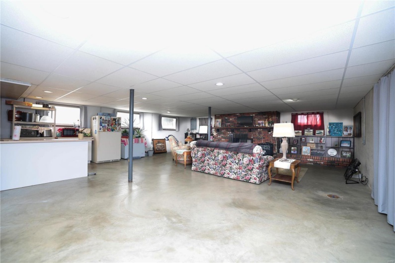 Below grade area with a paneled ceiling and freestanding refrigerator