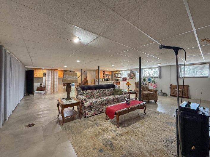 Living area featuring concrete floors, stairs, and a drop ceiling