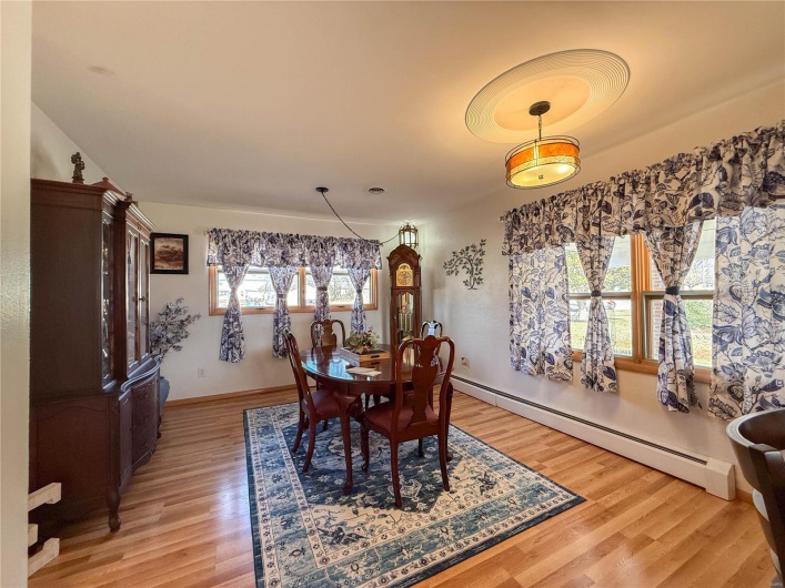 Dining room with a baseboard radiator, light wood-style flooring, and baseboards