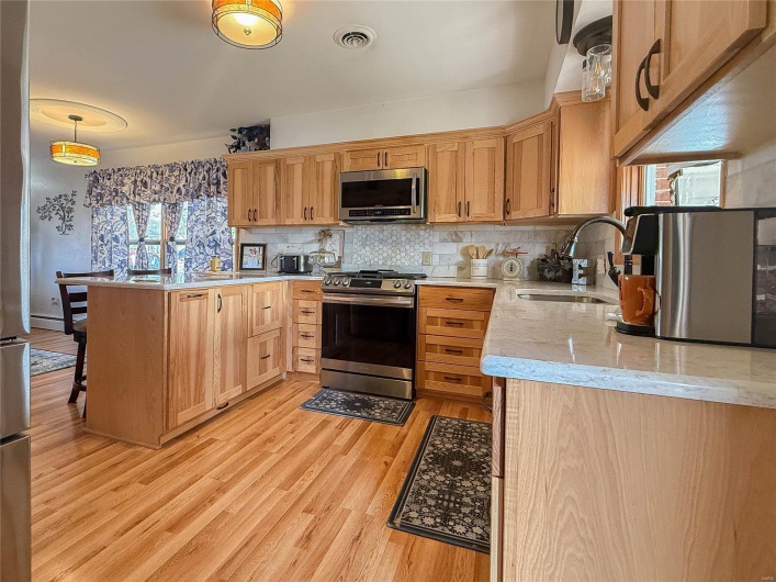 Kitchen featuring visible vents, light wood-style flooring, a sink, stainless steel appliances, and backsplash