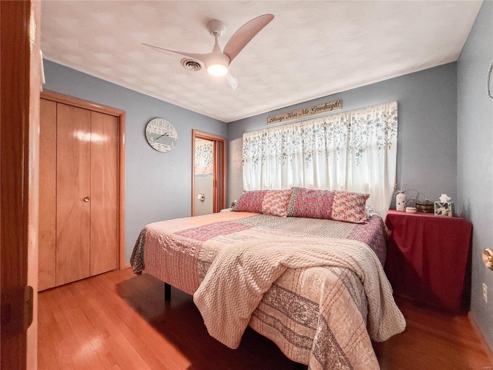 Bedroom with a ceiling fan, visible vents, and wood finished floors