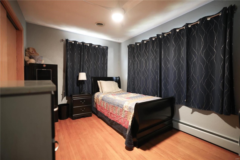 Bedroom featuring light wood finished floors, baseboard heating, and visible vents