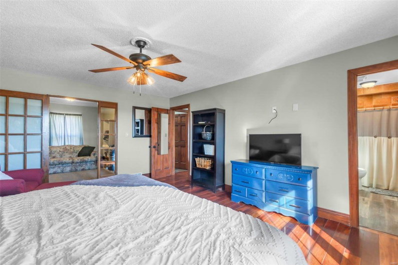 Bedroom with ceiling fan, baseboards, dark wood finished floors, and a textured ceiling