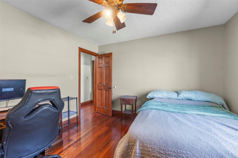 Bedroom with a textured ceiling, ceiling fan, dark wood-type flooring, and baseboards