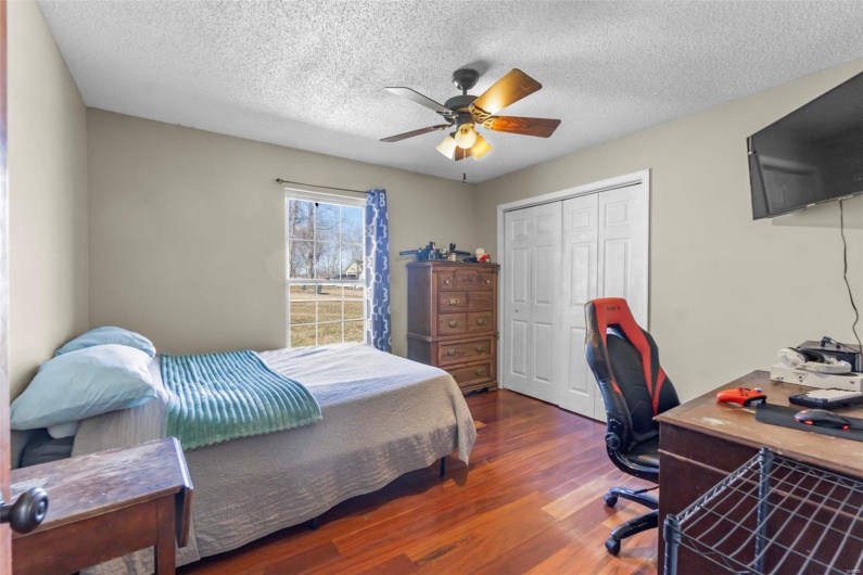 Bedroom featuring a textured ceiling, dark wood-style flooring, a closet, and a ceiling fan
