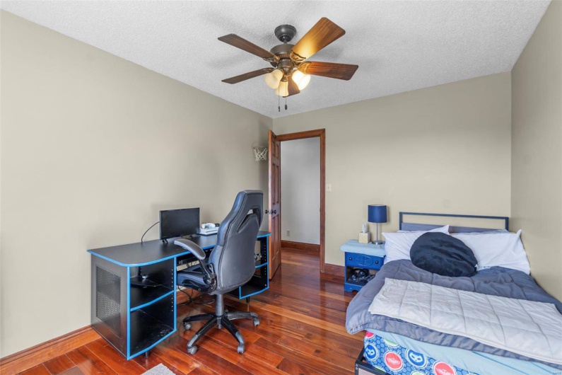 Bedroom with ceiling fan, baseboards, dark wood finished floors, and a textured ceiling