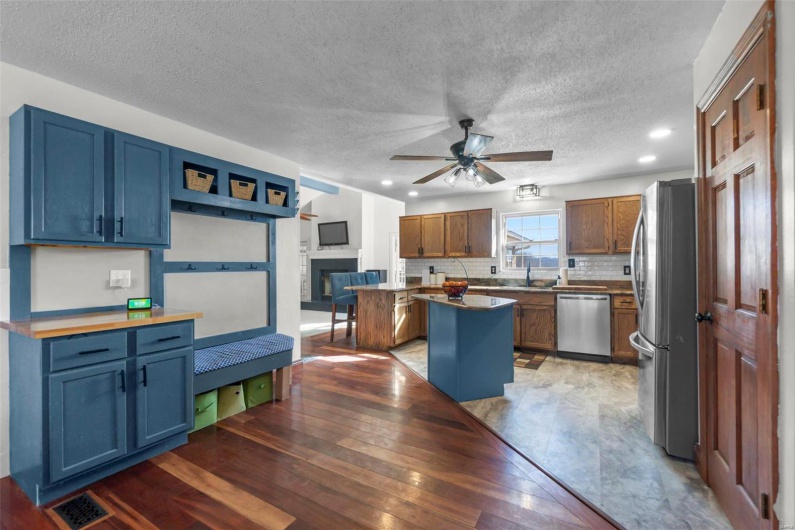 Kitchen featuring stainless steel appliances, a kitchen island, blue cabinetry, tasteful backsplash, and a glass covered fireplace