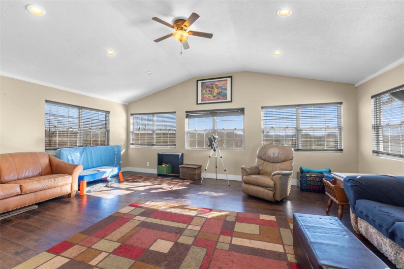 Living area with baseboards, lofted ceiling, dark wood-style floors, ceiling fan, and recessed lighting