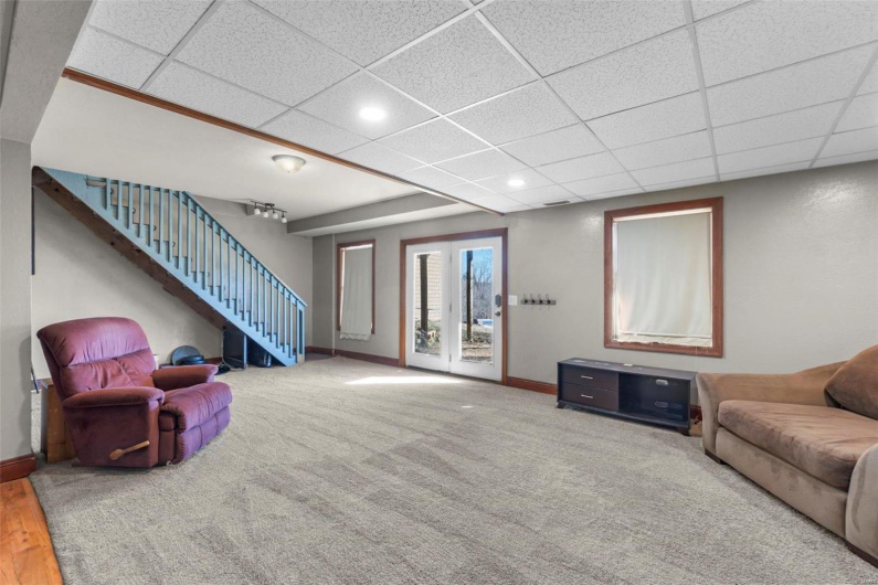 Living area with stairs, a paneled ceiling, and baseboards