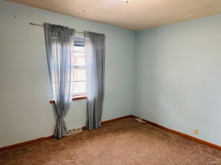 Carpeted spare room featuring baseboards