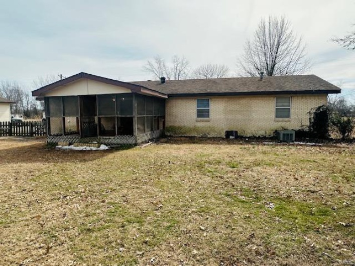 Back of property with a sunroom, fence, a yard, central air condition unit, and brick siding