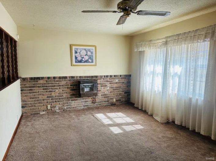Empty room with a brick fireplace, a textured ceiling, and carpet flooring