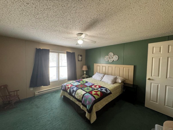 Bedroom featuring a textured ceiling, a baseboard radiator, carpet flooring, and a ceiling fan