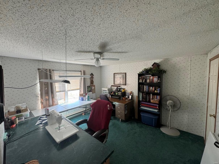 Office featuring wallpapered walls, a textured ceiling, and carpet flooring