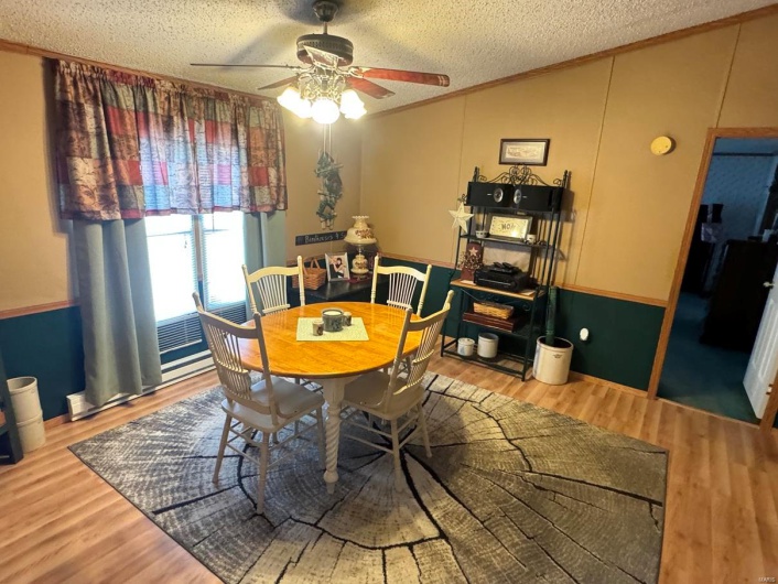 Dining room featuring a ceiling fan, lofted ceiling, wood finished floors, crown molding, and a textured ceiling