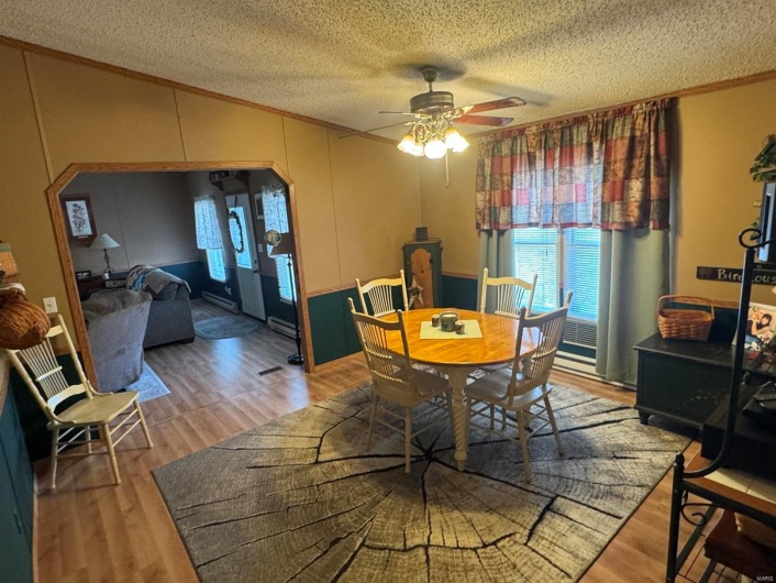 Dining space featuring arched walkways, a textured ceiling, lofted ceiling, light wood-style flooring, and crown molding