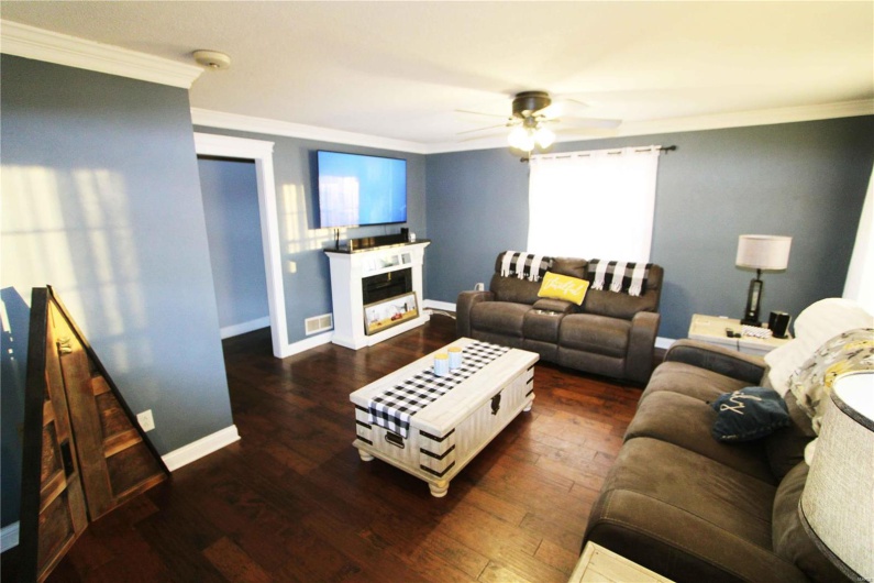 Living area with ornamental molding, a glass covered fireplace, and hardwood / wood-style flooring