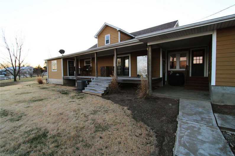 Back of house with a porch, a lawn, and central air condition unit