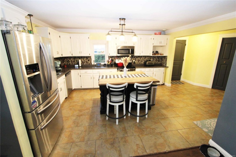Kitchen with dark countertops, backsplash, stainless steel appliances, and crown molding