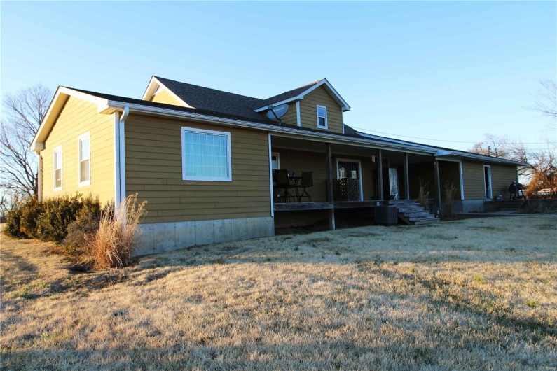 View of front of home featuring a porch, cooling unit, and a front yard