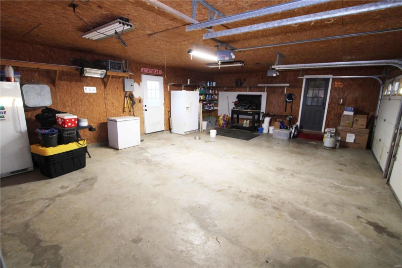 Garage featuring refrigerator, freestanding refrigerator, white fridge with ice dispenser, and a garage door opener