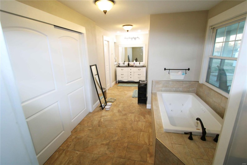 Bathroom with a jetted tub, vanity, and baseboards