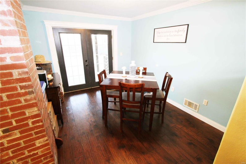 Dining area with dark wood-style floors, french doors, visible vents, and crown molding