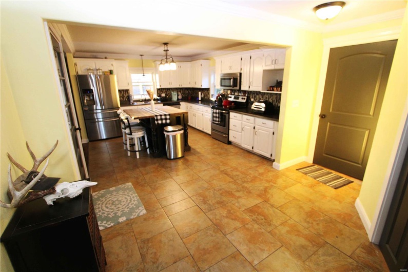 Kitchen featuring decorative backsplash, appliances with stainless steel finishes, ornamental molding, a center island, and white cabinetry