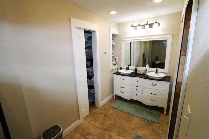 Full bath with a walk in closet, double vanity, recessed lighting, a sink, and baseboards