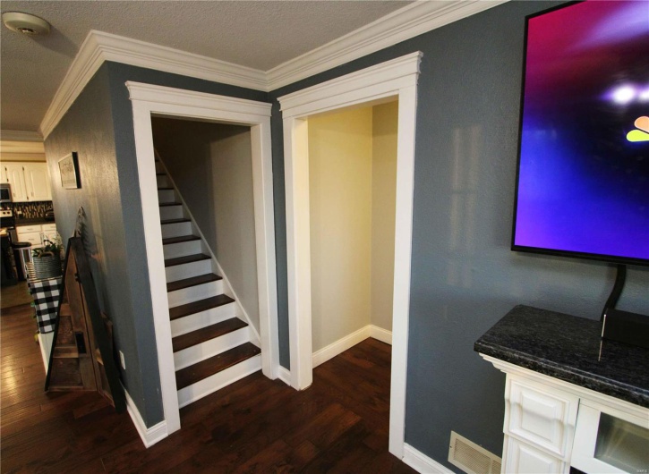 Staircase with ornamental molding, visible vents, baseboards, and wood finished floors