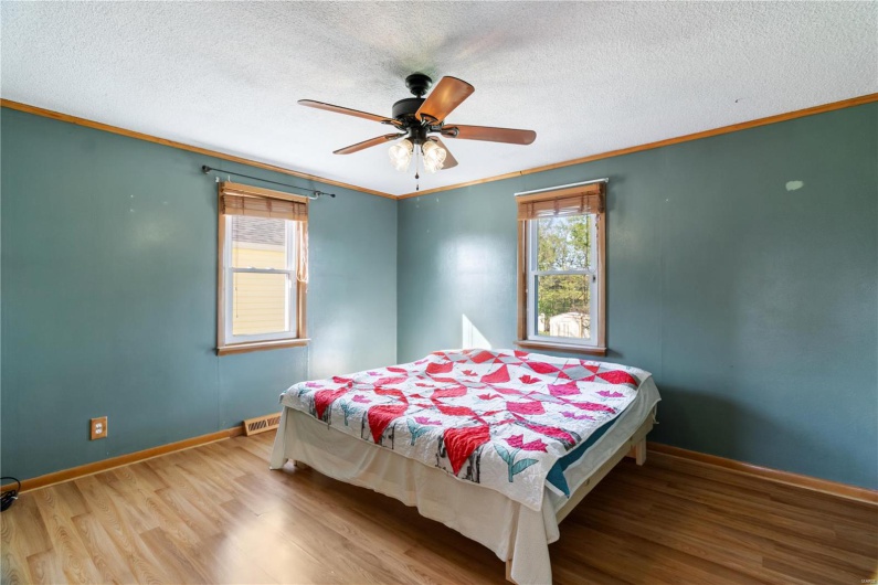 Bedroom featuring multiple windows, wood finished floors, visible vents, and ornamental molding