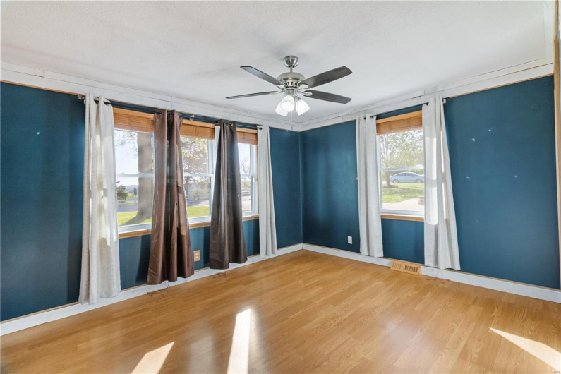 Unfurnished room with wood finished floors, visible vents, baseboards, and ceiling fan