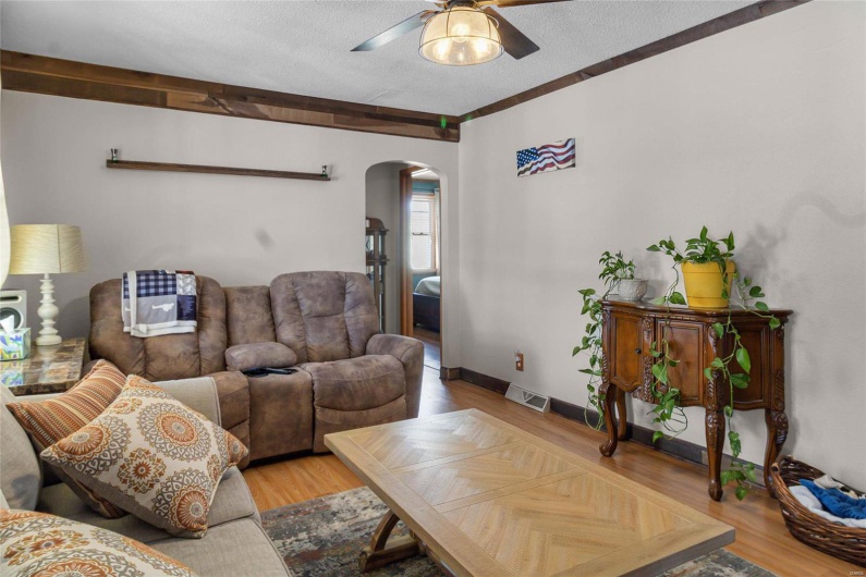 Living area with arched walkways, visible vents, a ceiling fan, a textured ceiling, and baseboards