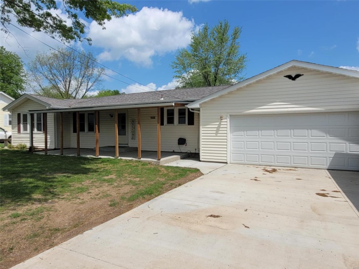 Single story home featuring a shingled roof, an attached garage, concrete driveway, and a front lawn