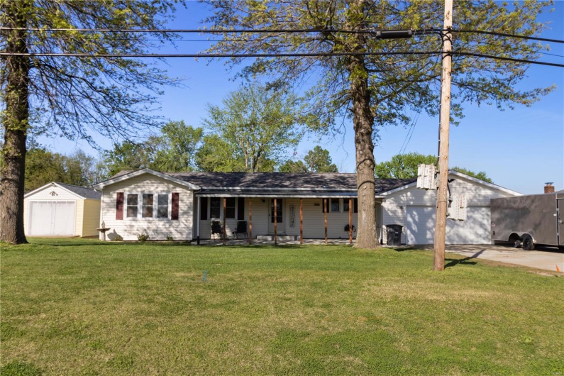 View of front of house featuring a shed, an outbuilding, a porch, and a front yard
