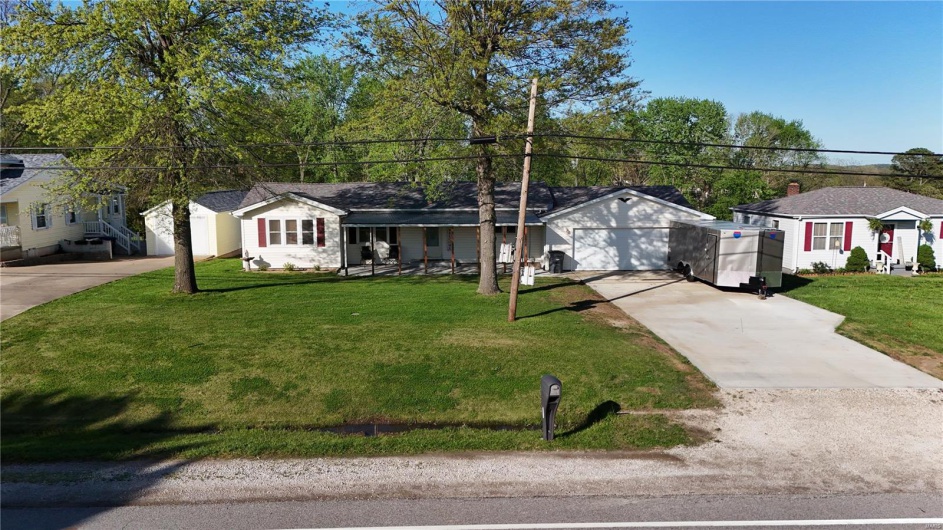 Ranch-style home with a garage, a front lawn, and driveway