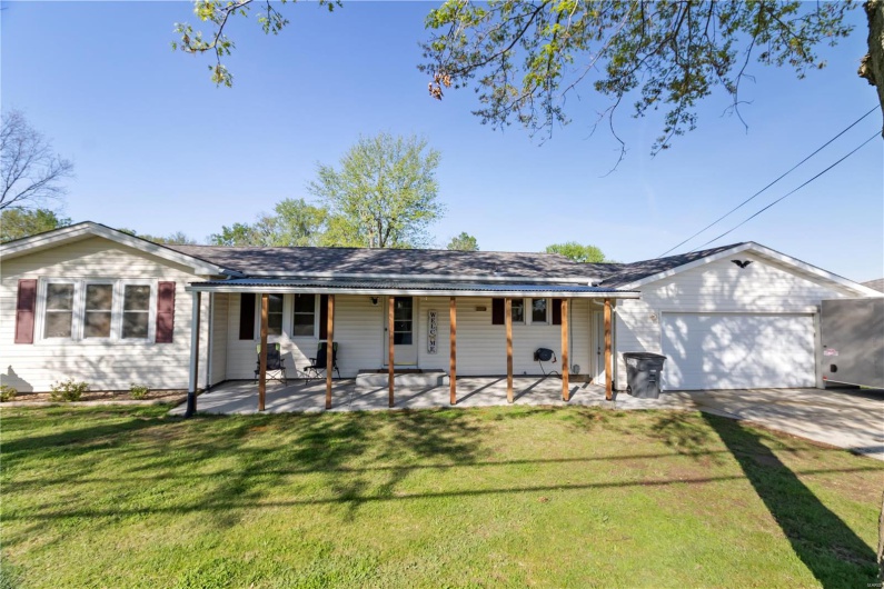 Single story home featuring driveway, a front lawn, covered porch, and an attached garage