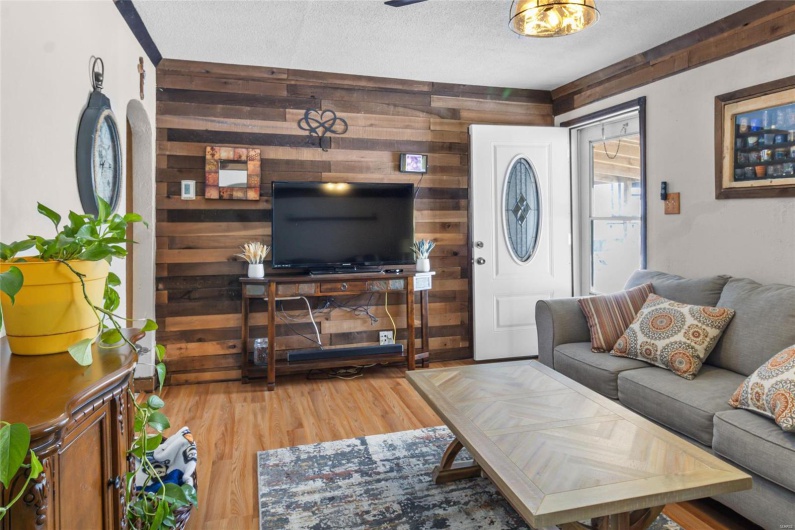 Living room featuring wooden walls, a textured ceiling, arched walkways, and wood finished floors