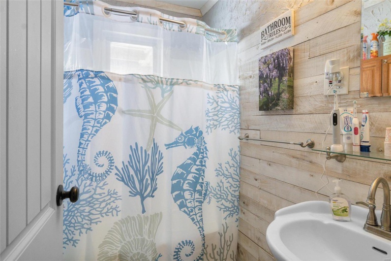 Bathroom with curtained shower, a sink, and wooden walls