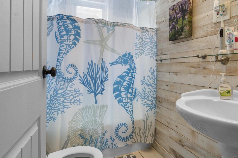 Bathroom featuring wood walls, tile patterned flooring, a sink, and toilet