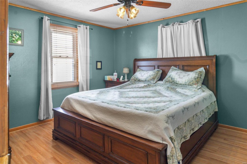 Bedroom featuring ornamental molding, ceiling fan, a textured ceiling, light wood-type flooring, and baseboards