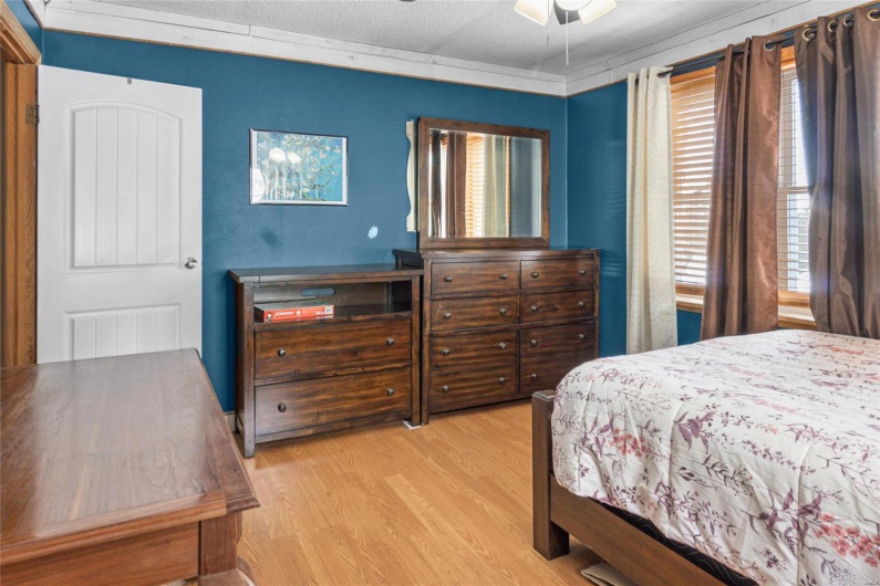 Bedroom with light wood-type flooring, ceiling fan, and a textured ceiling