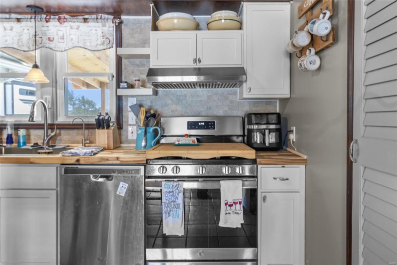 Kitchen with stainless steel range with gas stovetop, under cabinet range hood, dishwashing machine, and white cabinetry