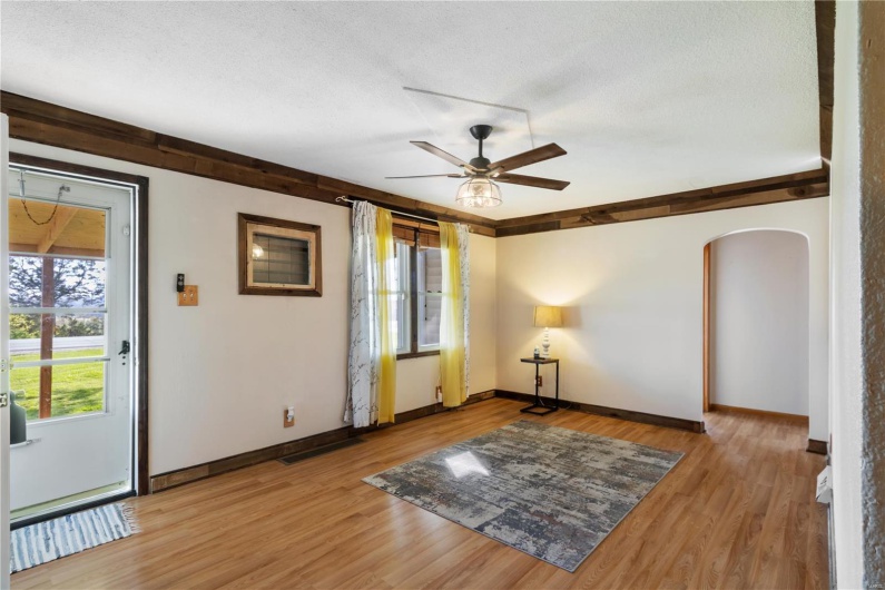 Spare room featuring arched walkways, baseboards, light wood-type flooring, a ceiling fan, and a textured ceiling