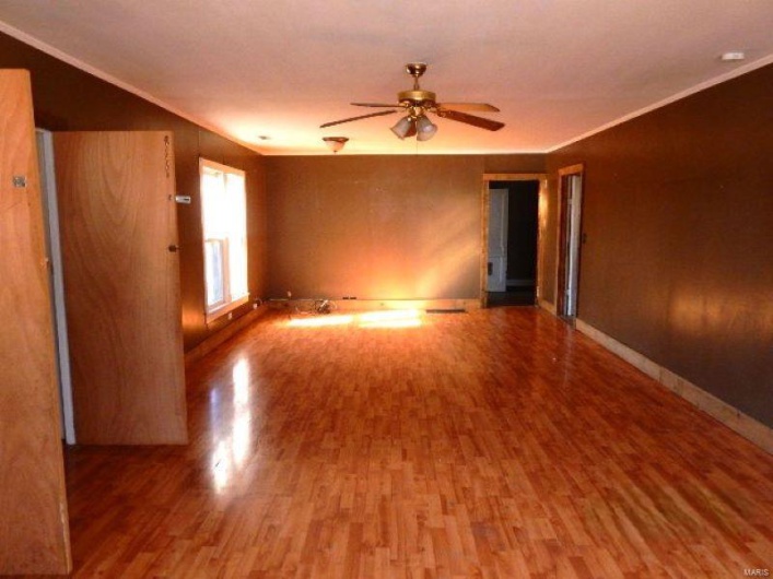 Spare room featuring ornamental molding, a ceiling fan, baseboards, and wood finished floors