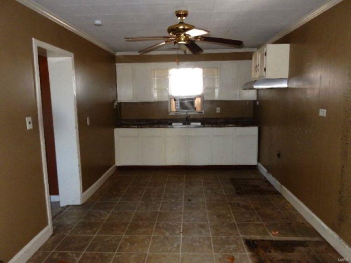 Kitchen with dark countertops, ceiling fan, ornamental molding, and a sink
