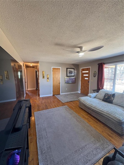 Unfurnished bedroom with baseboards, a textured ceiling, a ceiling fan, and wood finished floors